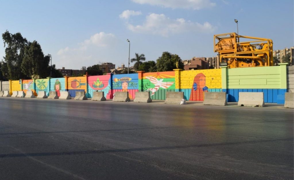 في ظل أهرامات الجيزة الـ ضخمة، يقف جدار خرساني على جانب طريق القاهرة الإسكندرية السريع.